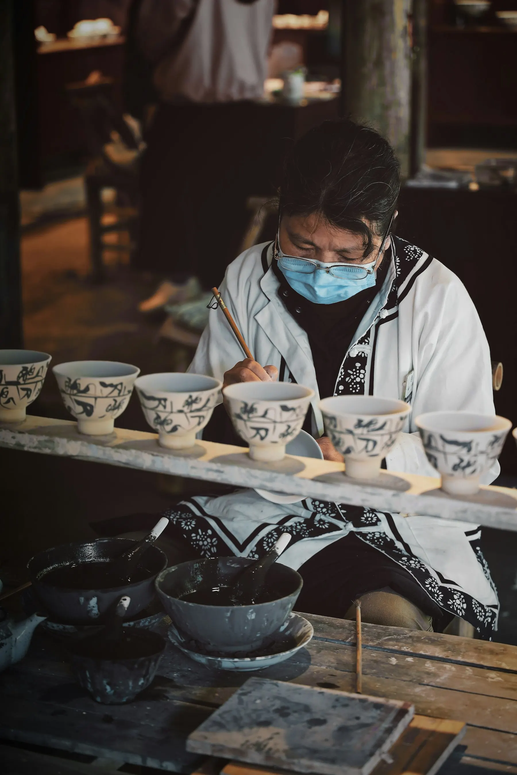 A potter arranging hand-painted porcelain bowls