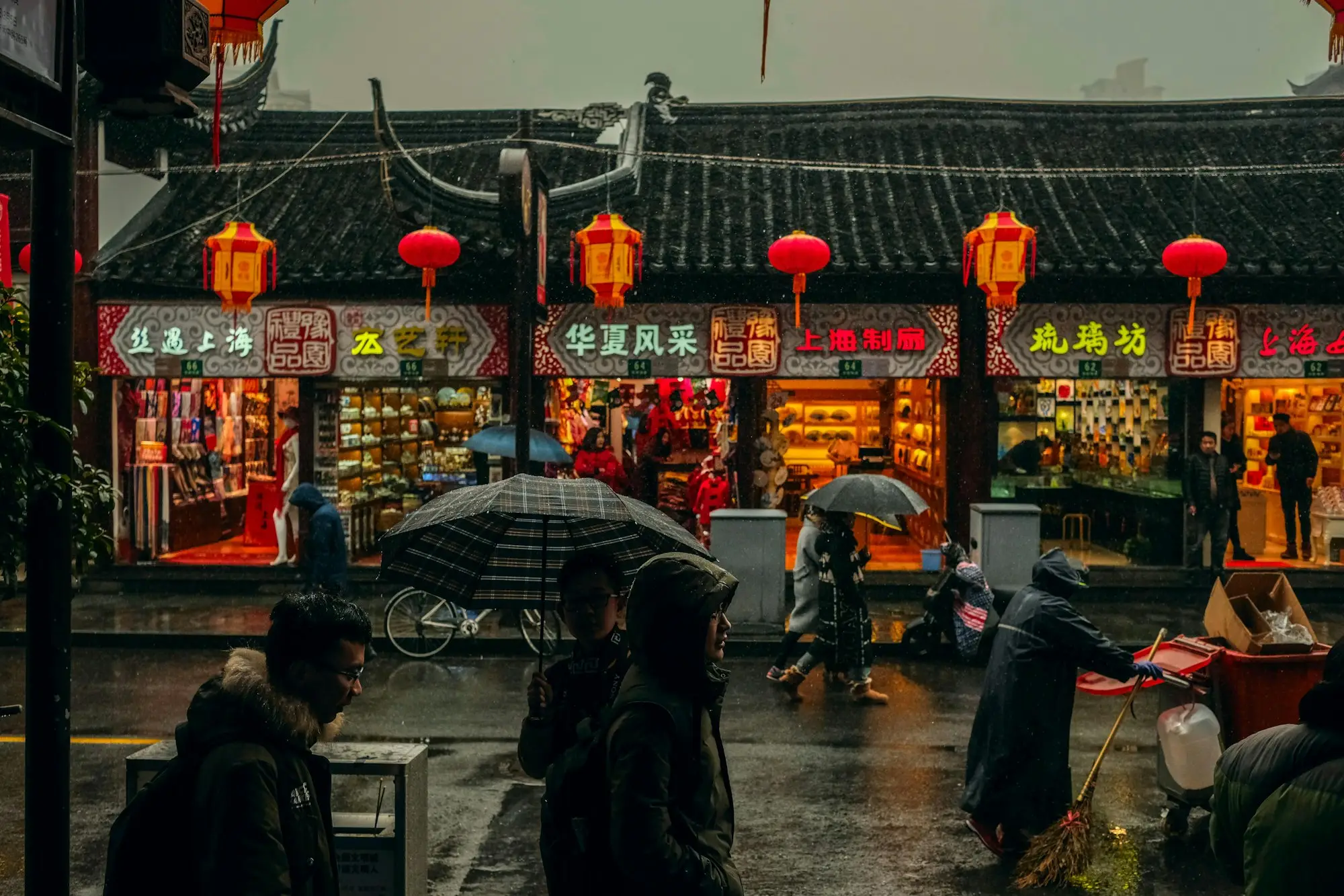 Early evening rain on a shopping street in Shanghai, as the shopfronts switch on